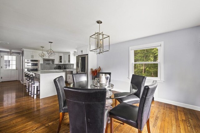 dining area with baseboards, a chandelier, a wealth of natural light, and dark wood-type flooring