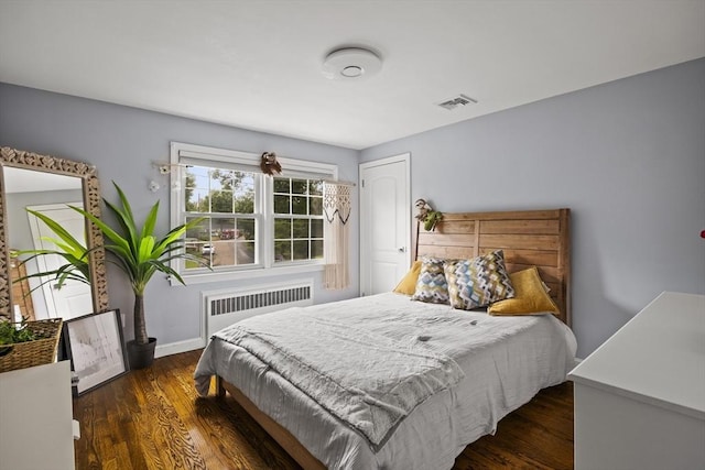 bedroom featuring baseboards, visible vents, radiator, and wood finished floors