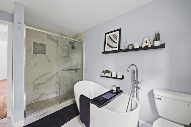 bathroom with a stall shower, toilet, a freestanding bath, and marble finish floor