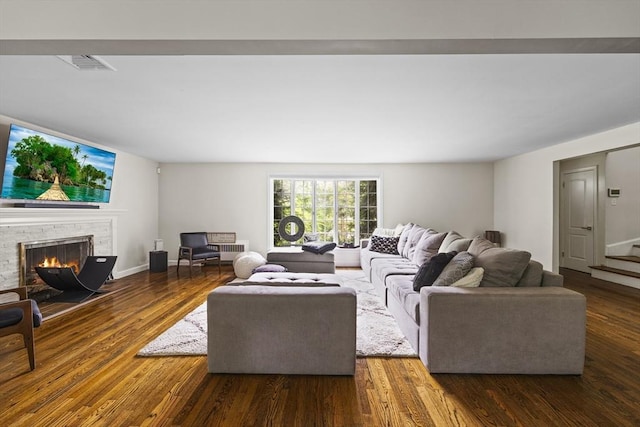 living area featuring stairs, visible vents, wood finished floors, and a fireplace