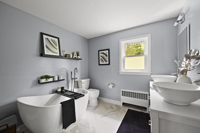 bathroom with a sink, a freestanding tub, marble finish floor, double vanity, and radiator heating unit