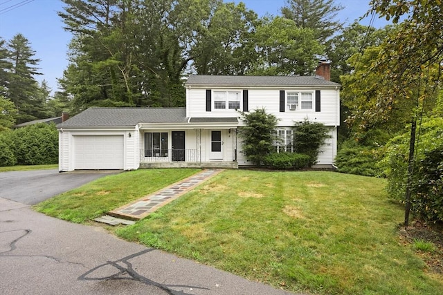 traditional-style house with a porch, a front yard, driveway, a chimney, and an attached garage