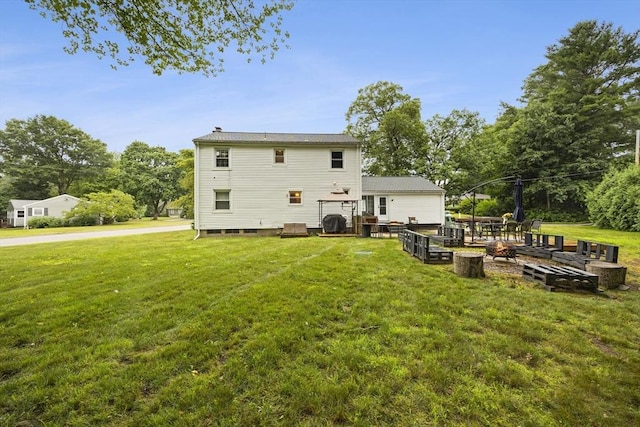 rear view of house featuring a lawn, a fire pit, a chimney, and a deck