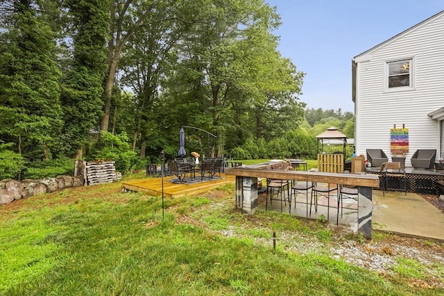 view of yard with outdoor dining space, a wooden deck, a gazebo, and a patio area