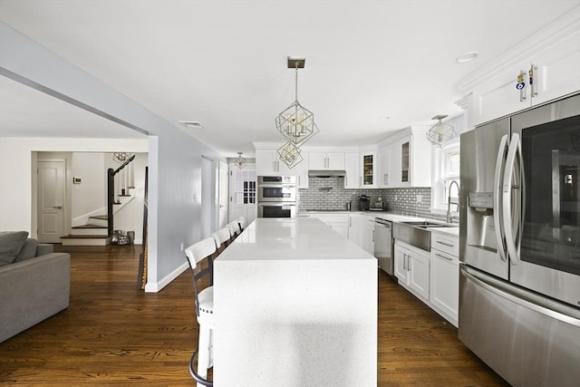 kitchen with backsplash, a sink, appliances with stainless steel finishes, and white cabinetry