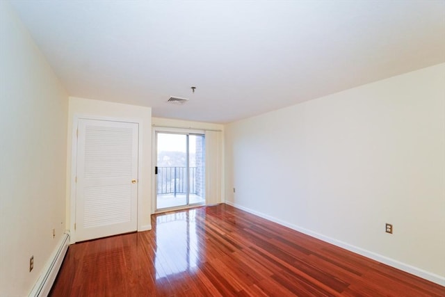 unfurnished room featuring baseboard heating and hardwood / wood-style floors