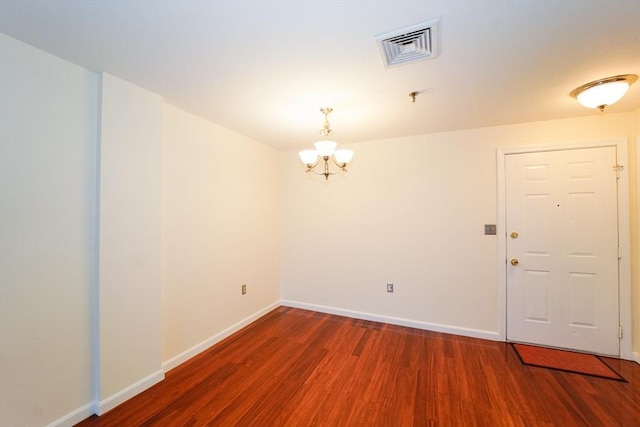 unfurnished room featuring wood-type flooring and an inviting chandelier