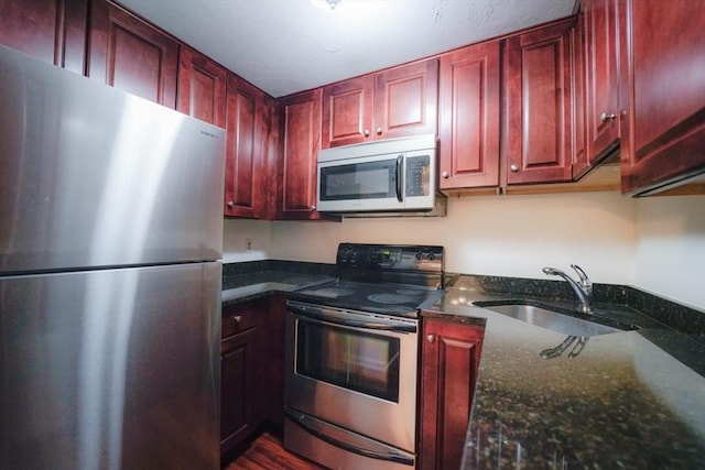 kitchen with dark stone countertops, sink, and appliances with stainless steel finishes