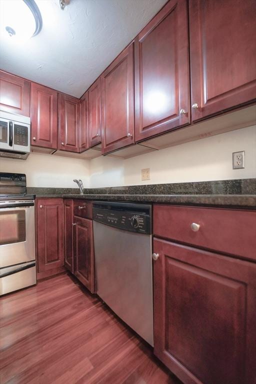 kitchen with sink, stainless steel appliances, and hardwood / wood-style flooring