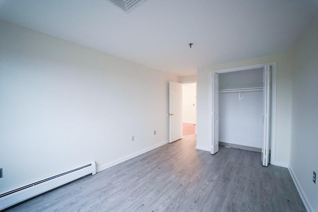 unfurnished bedroom with hardwood / wood-style flooring, baseboard heating, and a closet