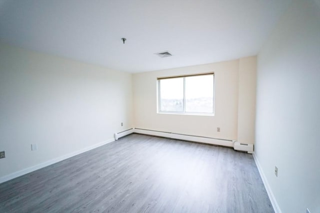 unfurnished room with baseboard heating and dark wood-type flooring