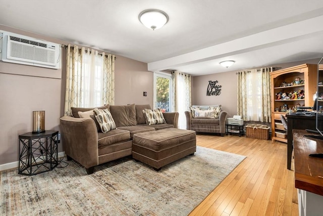 living room featuring a wall unit AC, baseboards, and light wood-type flooring