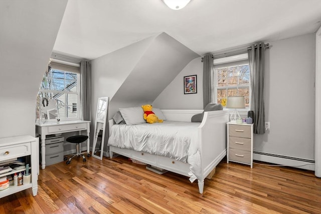 bedroom featuring lofted ceiling, multiple windows, light wood-style floors, and baseboard heating