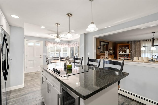 kitchen with black appliances, wine cooler, light wood-style floors, white cabinets, and a baseboard radiator