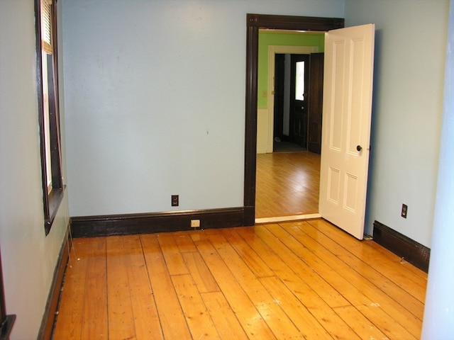 spare room featuring a baseboard heating unit, a healthy amount of sunlight, and light wood-type flooring