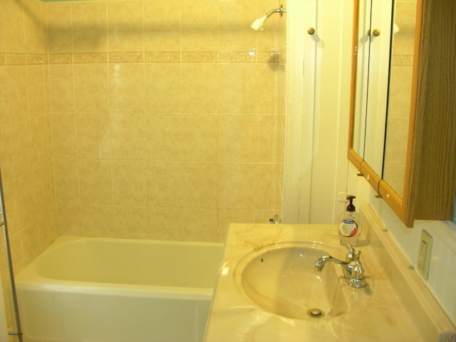 bathroom with tiled shower / bath combo and vanity