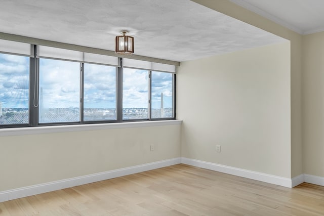 spare room featuring crown molding and light hardwood / wood-style floors