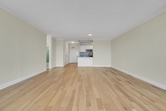 unfurnished living room with crown molding and light hardwood / wood-style floors