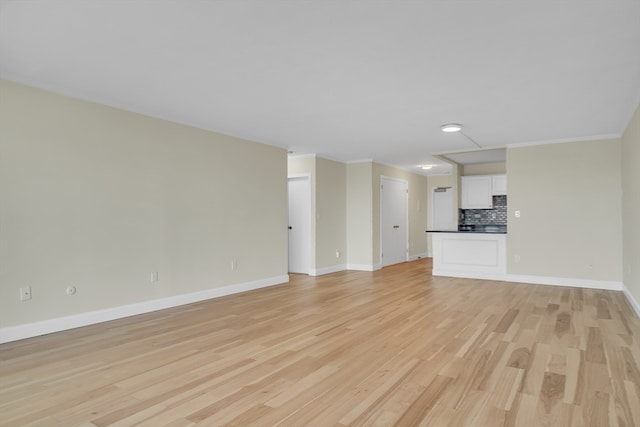 unfurnished living room with crown molding and light hardwood / wood-style floors