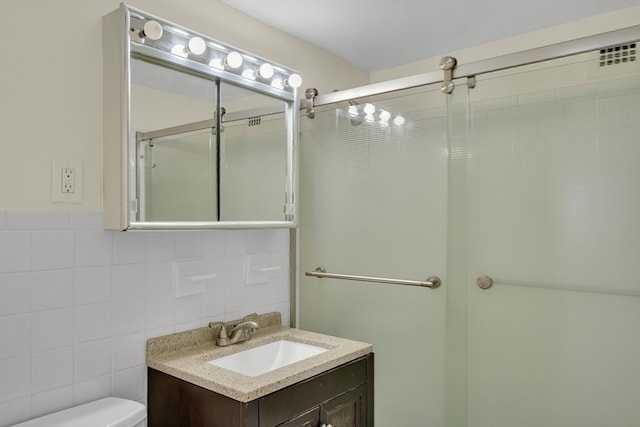 bathroom with vanity, toilet, an enclosed shower, and tile walls