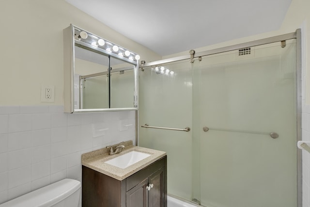 bathroom with vanity, toilet, tile walls, and a shower with shower door