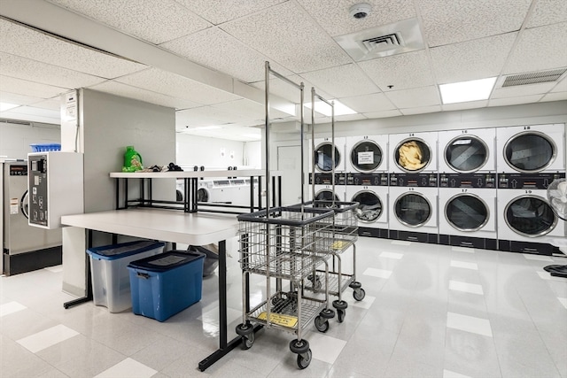 interior space featuring washing machine and clothes dryer, stacked washer and dryer, and a drop ceiling