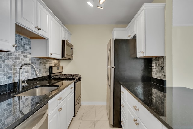 kitchen featuring dark stone counters, white cabinetry, stainless steel appliances, sink, and decorative backsplash