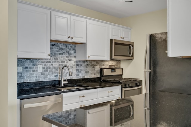 kitchen featuring white cabinets, dark stone countertops, appliances with stainless steel finishes, sink, and decorative backsplash