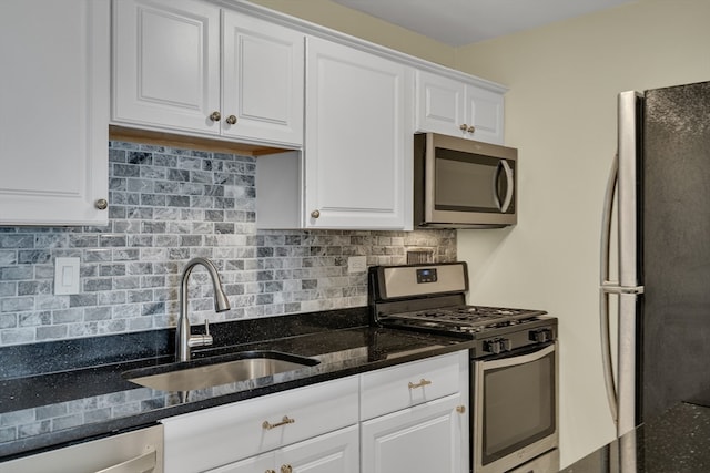 kitchen with backsplash, stainless steel appliances, sink, dark stone countertops, and white cabinets