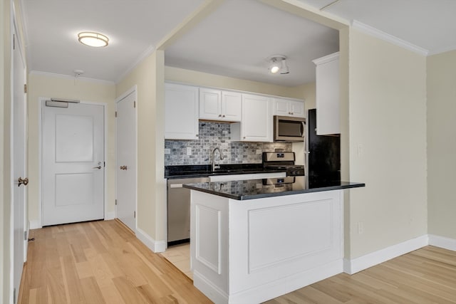 kitchen featuring light wood-type flooring, white cabinets, stainless steel appliances, and ornamental molding