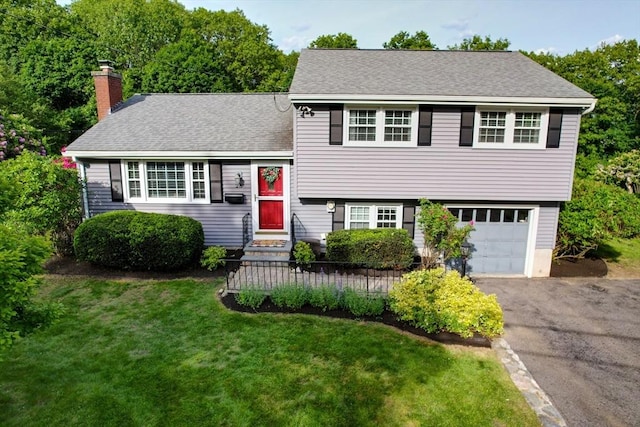 28 Foster Dr, Framingham, MA 01701 - tri-level home featuring a chimney, asphalt driveway, an attached garage, a front yard, and roof with shingles