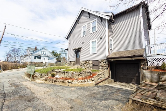 14 Fales St, Worcester, MA 01606 - view of home's exterior with roof with shingles, stone siding, fence, a garage, and aphalt driveway