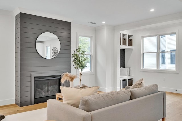 living room with wood finished floors, baseboards, a large fireplace, and recessed lighting