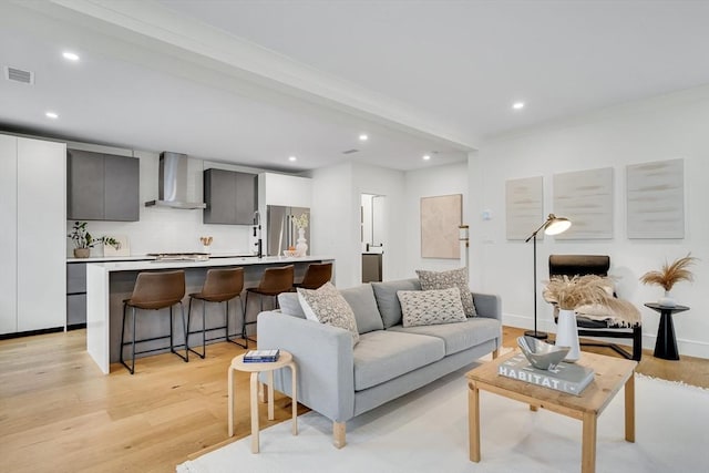 living area with light wood-style floors, recessed lighting, and beamed ceiling