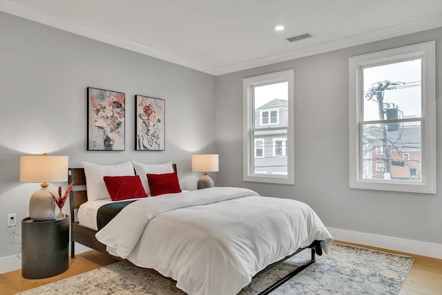bedroom featuring baseboards, wood finished floors, crown molding, and recessed lighting