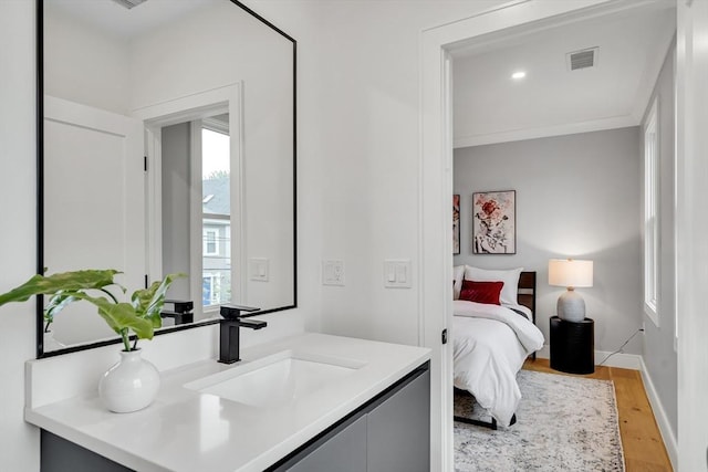 bedroom with a sink, light wood-type flooring, and baseboards