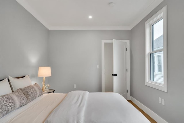bedroom featuring baseboards, wood finished floors, and crown molding