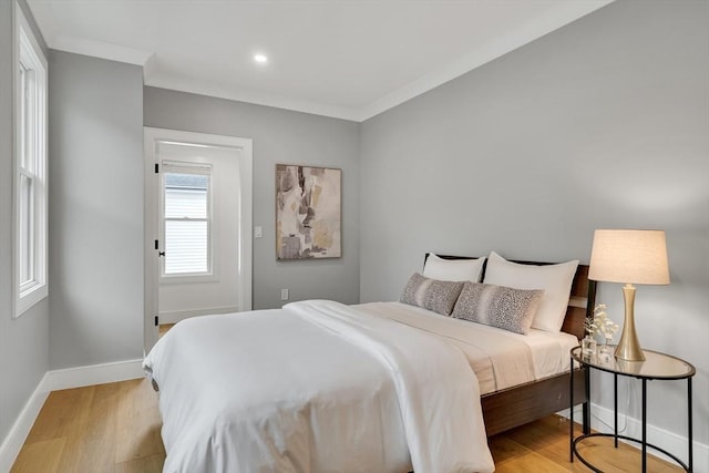 bedroom featuring baseboards, light wood-type flooring, recessed lighting, and crown molding