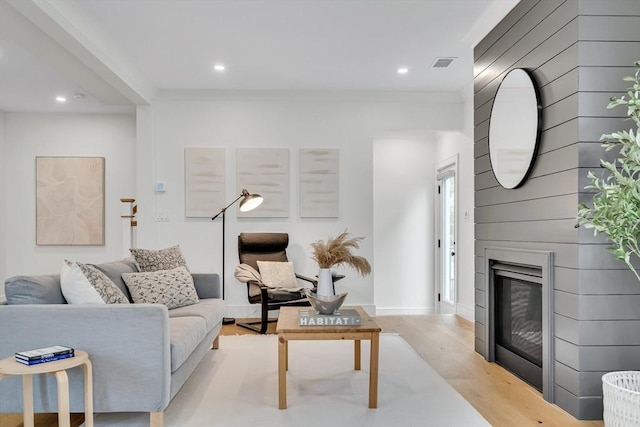 living room featuring wood finished floors, recessed lighting, crown molding, a large fireplace, and baseboards