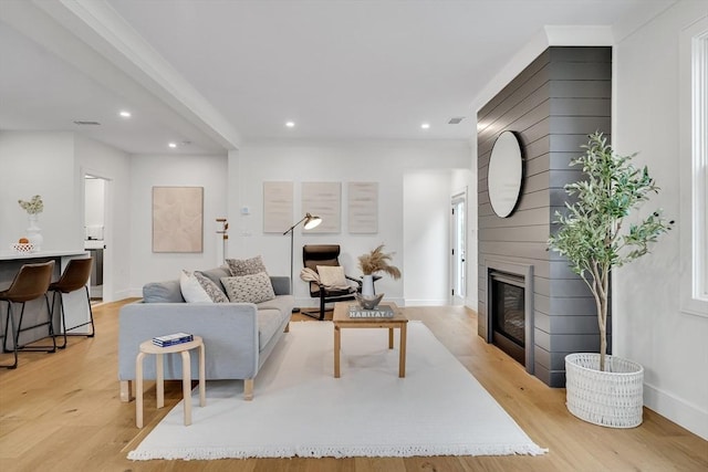 living area with recessed lighting, light wood-style flooring, baseboards, and a fireplace