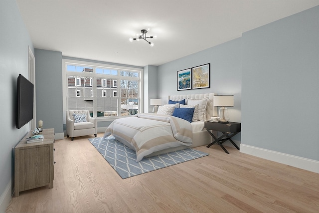 bedroom with light hardwood / wood-style flooring and an inviting chandelier