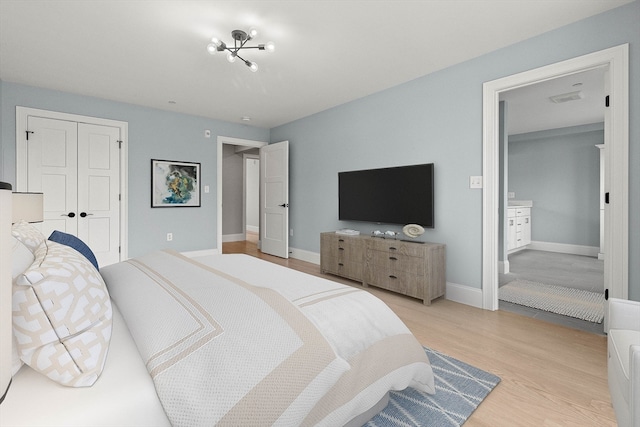 bedroom with a closet, light hardwood / wood-style flooring, and a chandelier