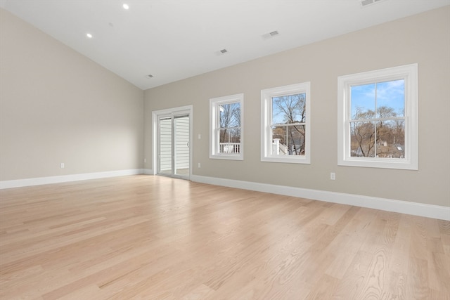 spare room featuring vaulted ceiling and light hardwood / wood-style floors