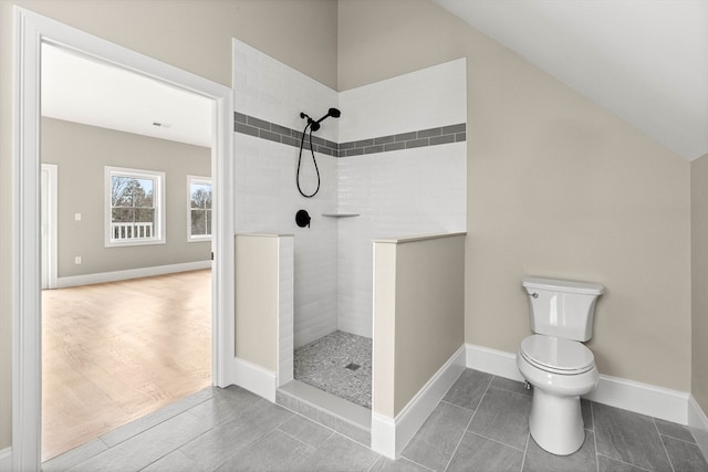 bathroom with toilet, hardwood / wood-style flooring, vaulted ceiling, and tiled shower