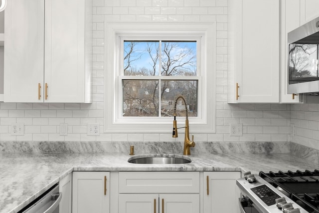 kitchen featuring appliances with stainless steel finishes, sink, white cabinetry, and light stone counters