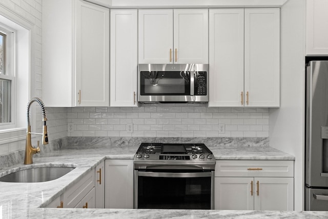 kitchen with appliances with stainless steel finishes, white cabinets, and sink