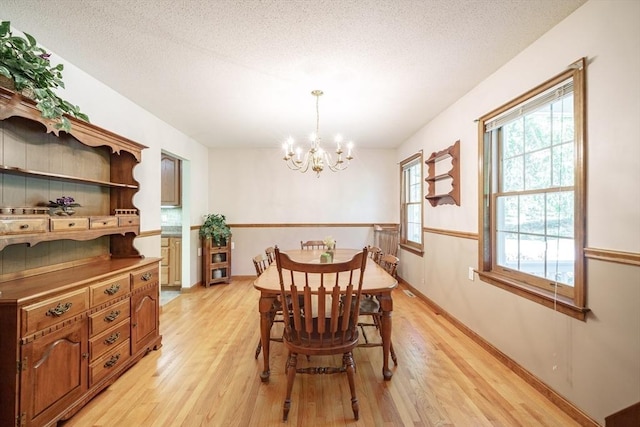 9 Lauren Ln, Southwick, MA 01077 - dining space with light wood-style flooring, a chandelier, a textured ceiling, and baseboards