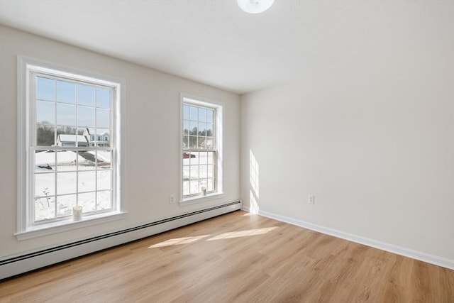 empty room featuring a baseboard radiator, light wood-style flooring, and baseboards