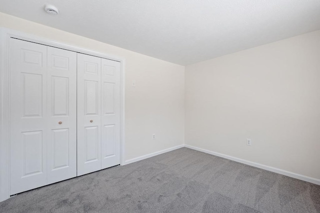 unfurnished bedroom featuring baseboards, a closet, and light colored carpet