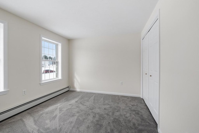 unfurnished bedroom with carpet floors, a baseboard radiator, a closet, and baseboards